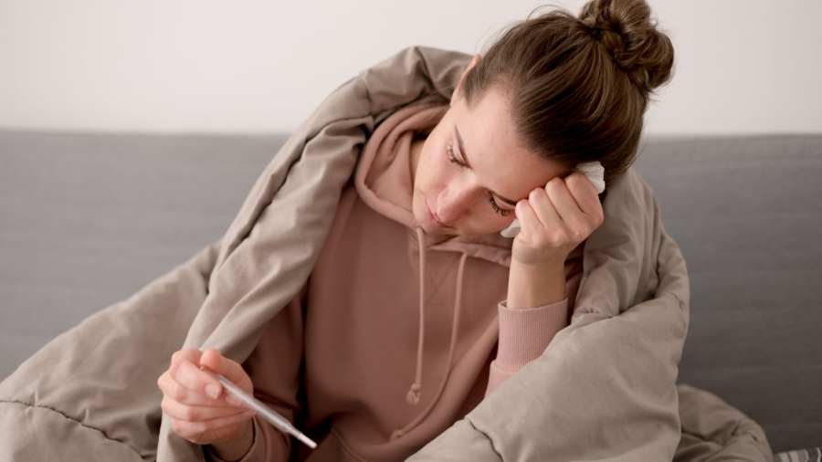 Жена, заразена с вирус, държи термометър