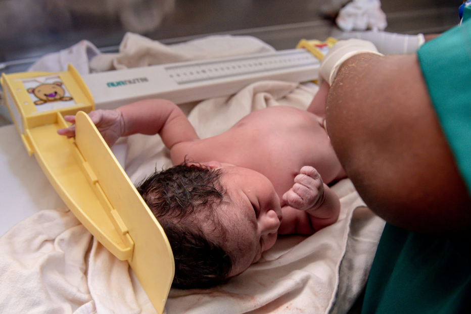 лекар измерва ръста на новородено бебе