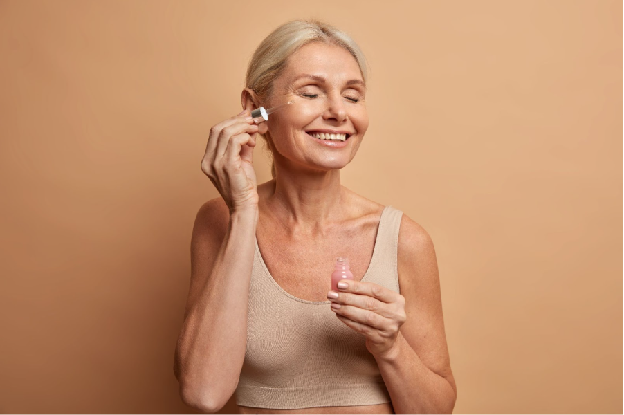 По-възрастна жена нанася серум на лицето си